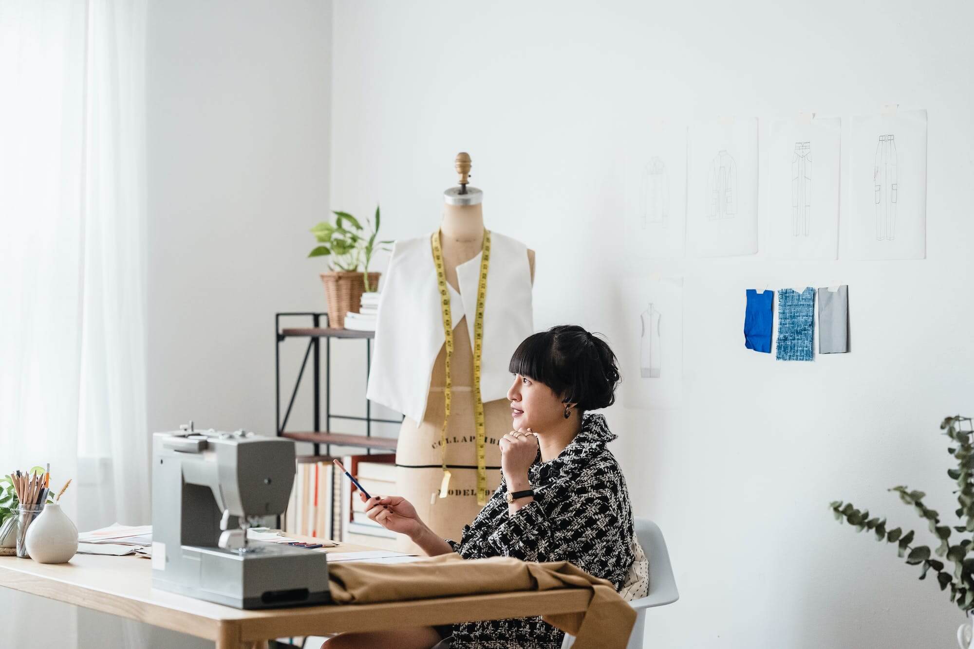 Photo by Michael Burrows: https://www.pexels.com/photo/pensive-asian-female-sewer-sitting-at-wooden-table-against-mannequin-in-atelier-7147965/